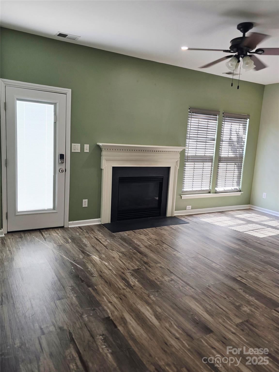 19025 Coachmans Trace Cornelius, NC 28031 - Photo 5 of 34 an empty room with wooden floor fireplace and windows