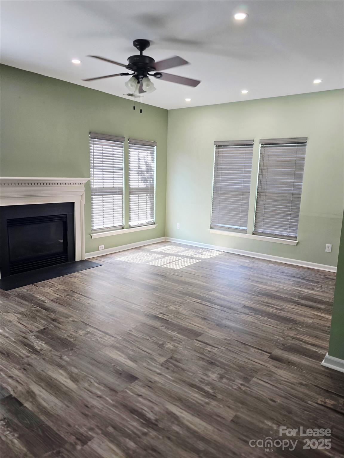 19025 Coachmans Trace Cornelius, NC 28031 - Photo 6 of 34 an empty room with wooden floor fireplace and windows