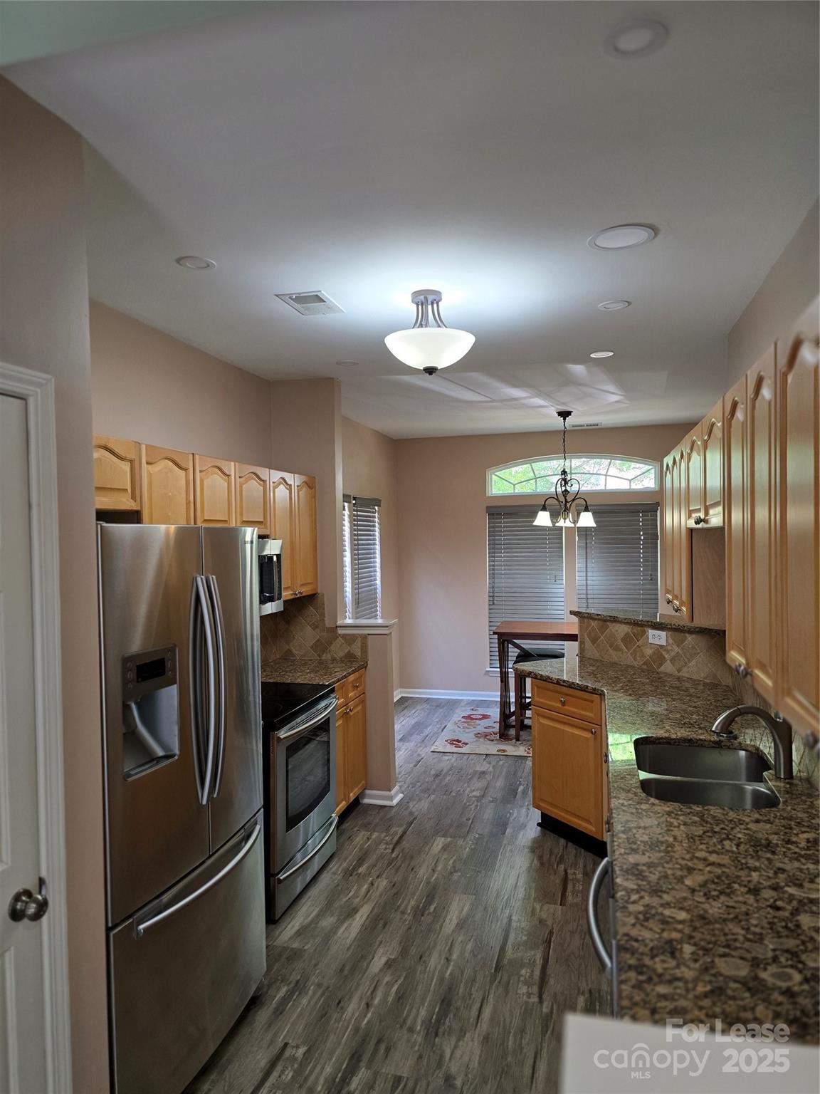 19025 Coachmans Trace Cornelius, NC 28031 - Photo 9 of 34 a kitchen with kitchen island granite countertop a refrigerator a stove a sink a dining table and chairs with wooden floor