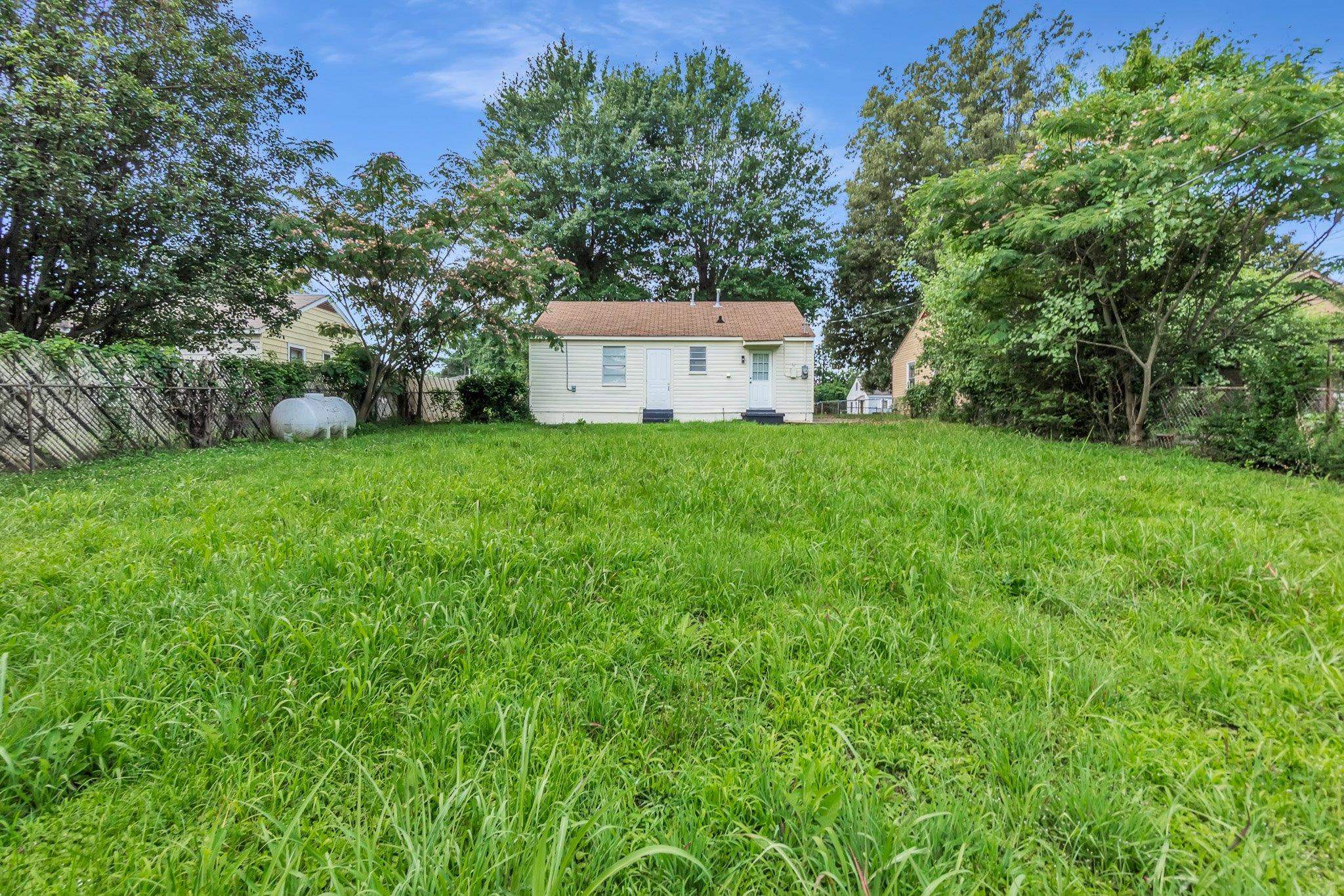 3186 Alta Road Memphis, TN 38109 - Photo 14 of 14 Expansive green lawn with mature trees and a detached structure featuring white siding and a brown shingle roof