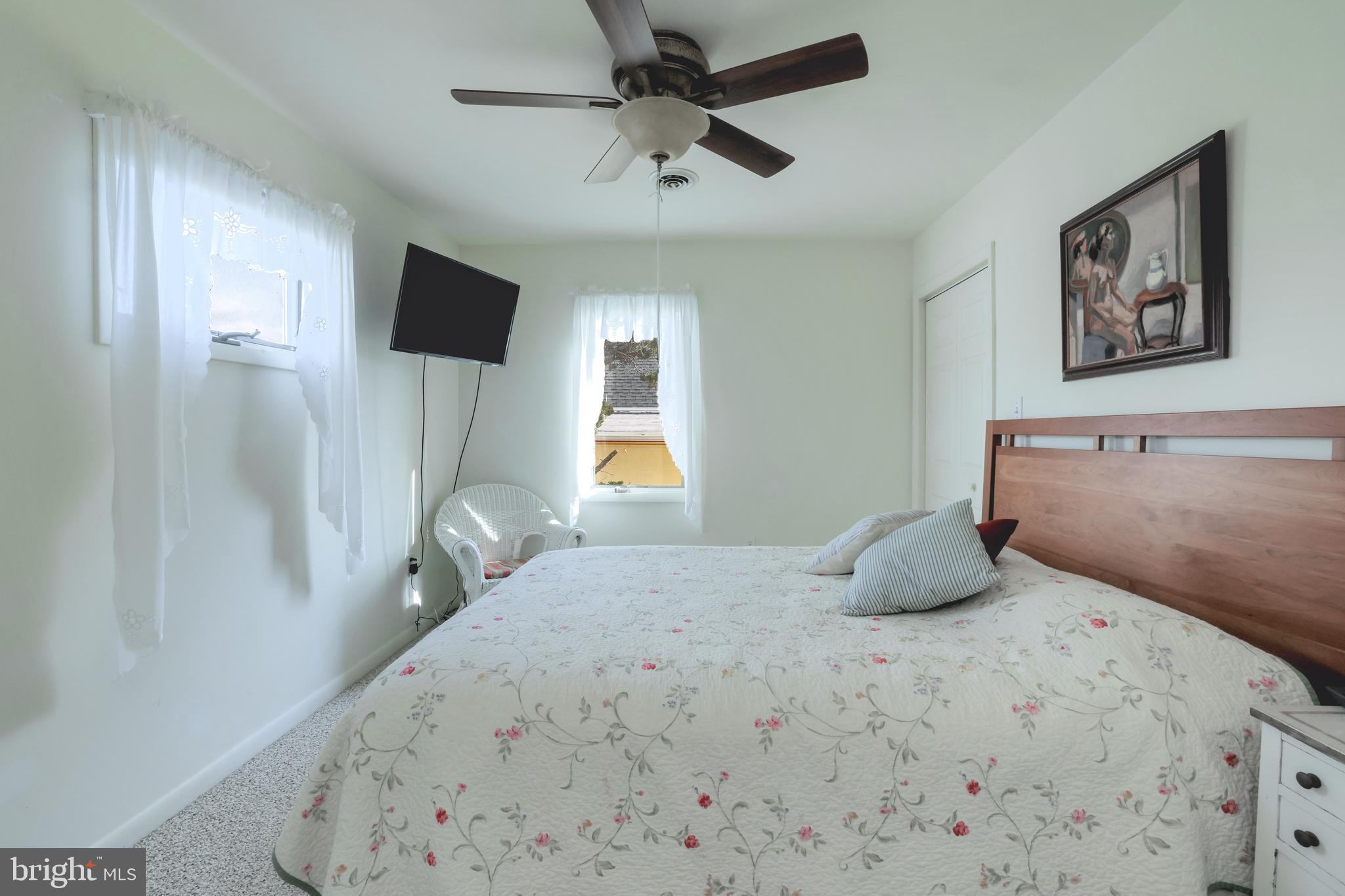 24 Maiden Lane Harvey Cedars, NJ 08008 - Photo 22 of 37 a bedroom with a bed a flat screen tv and a ceiling fan