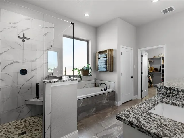 a bathroom with a granite countertop sink a mirror and a bathtub