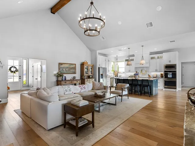 a living room with furniture kitchen view and a chandelier