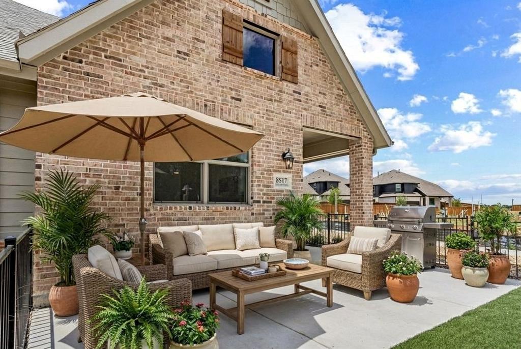 12831 Pne Rdg Trail Wylie, TX 75098 - Photo 9 of 12 a view of a patio with couches table and chairs under an umbrella with a fire pit