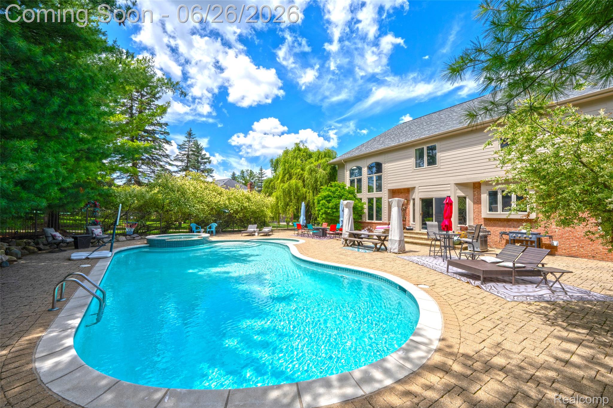 2619 Lambeth Park Rochester, MI 48306 - Photo 64 of 71 Expansive backyard featuring a large swimming pool with an integrated spa, extensive paver patio, mature trees, and a two-story home exterior with brick and siding finishes