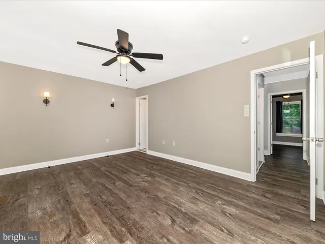 an empty room with wooden floor ceiling fan and windows