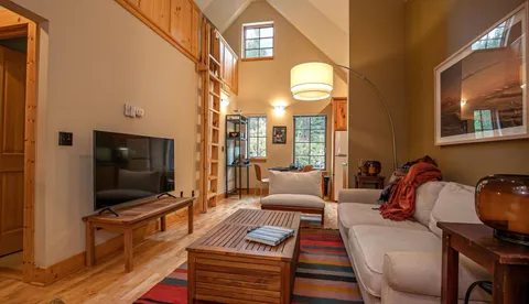 a living room with furniture a flat screen tv and a floor to ceiling window