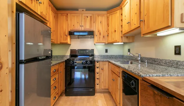 a kitchen with stainless steel appliances granite countertop a stove a sink and a refrigerator