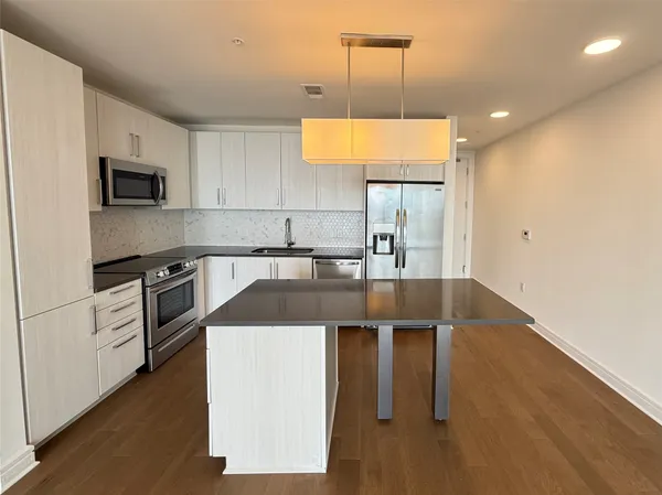 a kitchen with stainless steel appliances granite countertop a sink a stove and a refrigerator