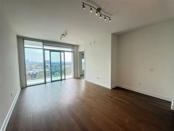 a view of an empty room with wooden floor and a window