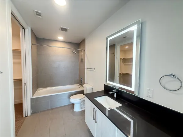 a bathroom with a granite countertop sink a toilet a mirror and bathtub