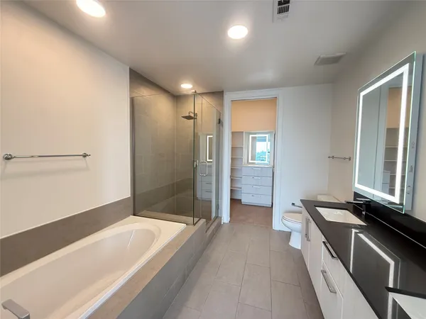 a spacious bathroom with a tub a sink and mirror