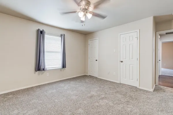an empty room with windows and fan