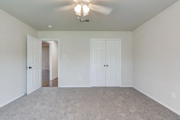 a view of an empty room with a chandelier fan