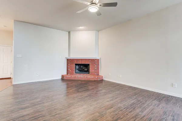 a view of an empty room with wooden floor and a fireplace