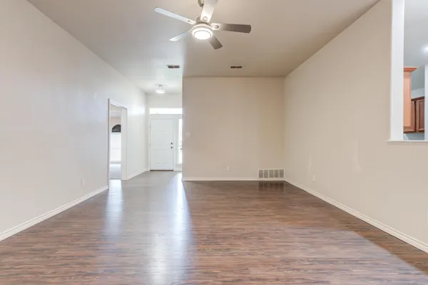 a view of an empty room with window and wooden floor