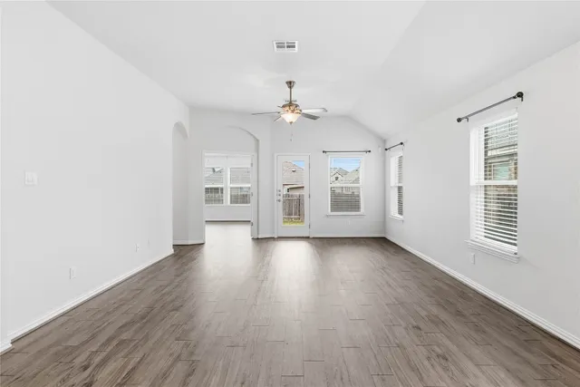 a view of an empty room with window and wooden floor
