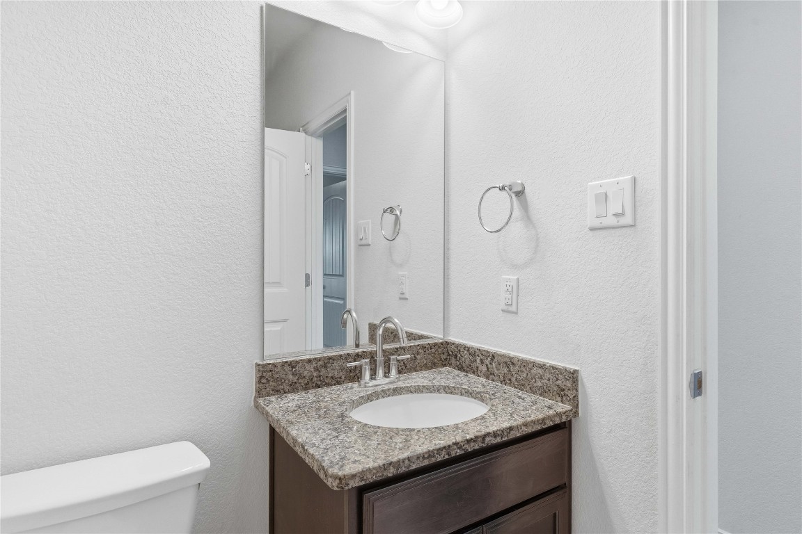 22020 Abigail Way Pflugerville, TX 78660 - Photo 21 of 25 a bathroom with a granite countertop sink a toilet and a mirror