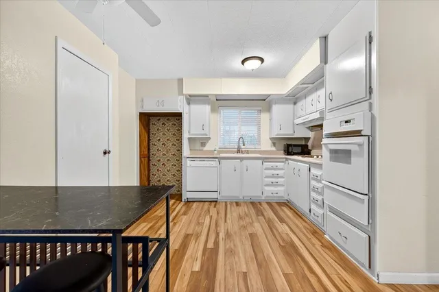 a kitchen with white cabinets and white appliances
