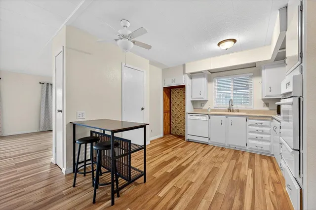 a kitchen with stainless steel appliances kitchen island wooden floors and white cabinets