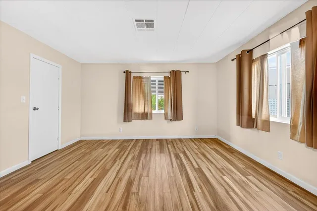 a view of an empty room with wooden floor and a window