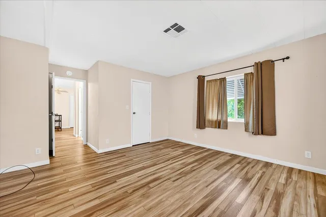 a view of an empty room with wooden floor and a window