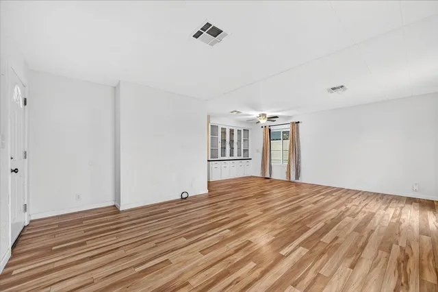 a view of empty room with wooden floor and fan