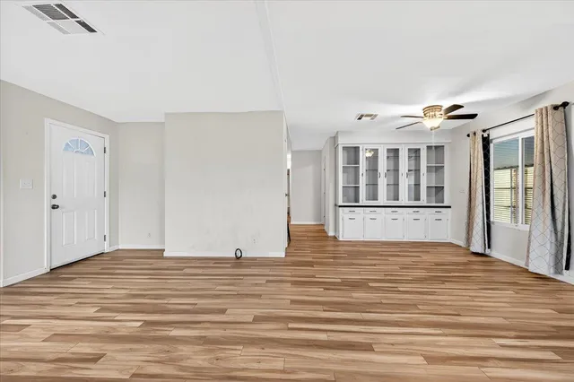 a view of an empty room with wooden floor and a window