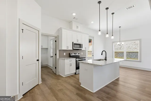 a large kitchen with stainless steel appliances kitchen island a large counter top a sink a stove and a refrigerator