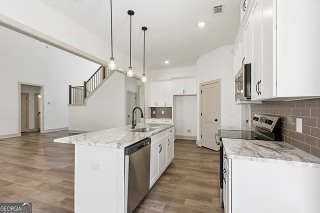 a large kitchen with stainless steel appliances kitchen island a large counter top a sink a stove and a refrigerator