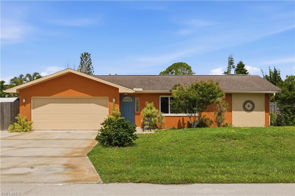 18588 Ocala Road Fort Myers, FL 33967 - Photo 1 of 17 Front exterior with a neutral-toned garage door, a blue entry door, and a circular decorative accent