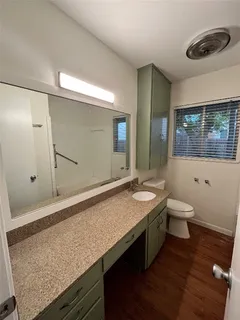 a bathroom with a granite countertop sink a toilet and a large mirror