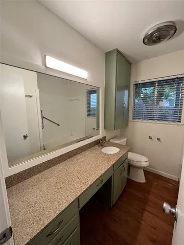 a bathroom with a granite countertop sink a toilet and a large mirror