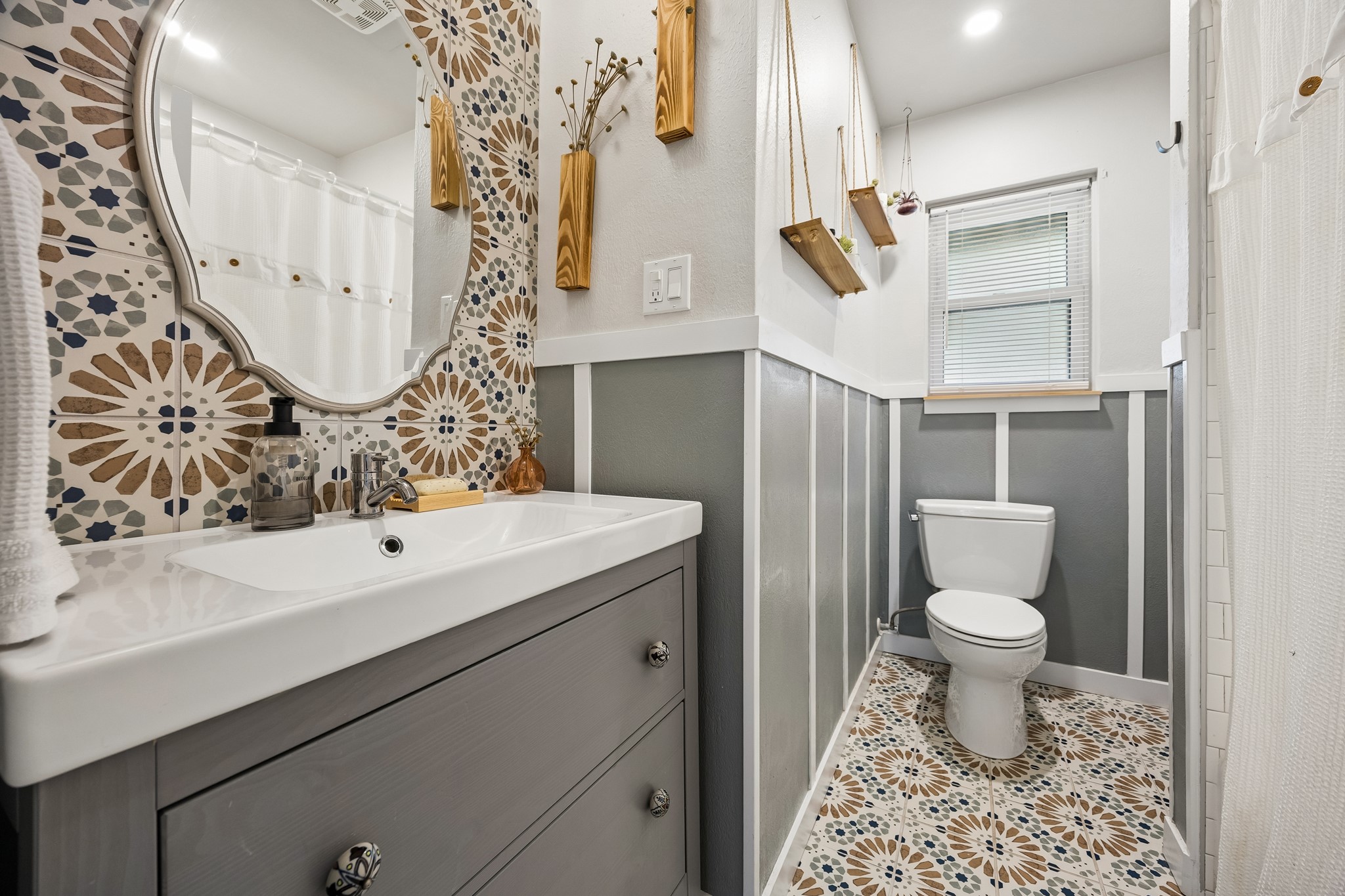4514 Warm Springs Road Houston, TX 77035 - Photo 24 of 31 This bathroom gives the home remarkable character. Featureing a unique design with patterned tile walls and floors, a modern faucet and antique porcelain drawer knobs. It includes a white tiled shower/tub combo. To the right of the toilet (not shown) is a wall of shelves and cabinets from floor to ceiling.