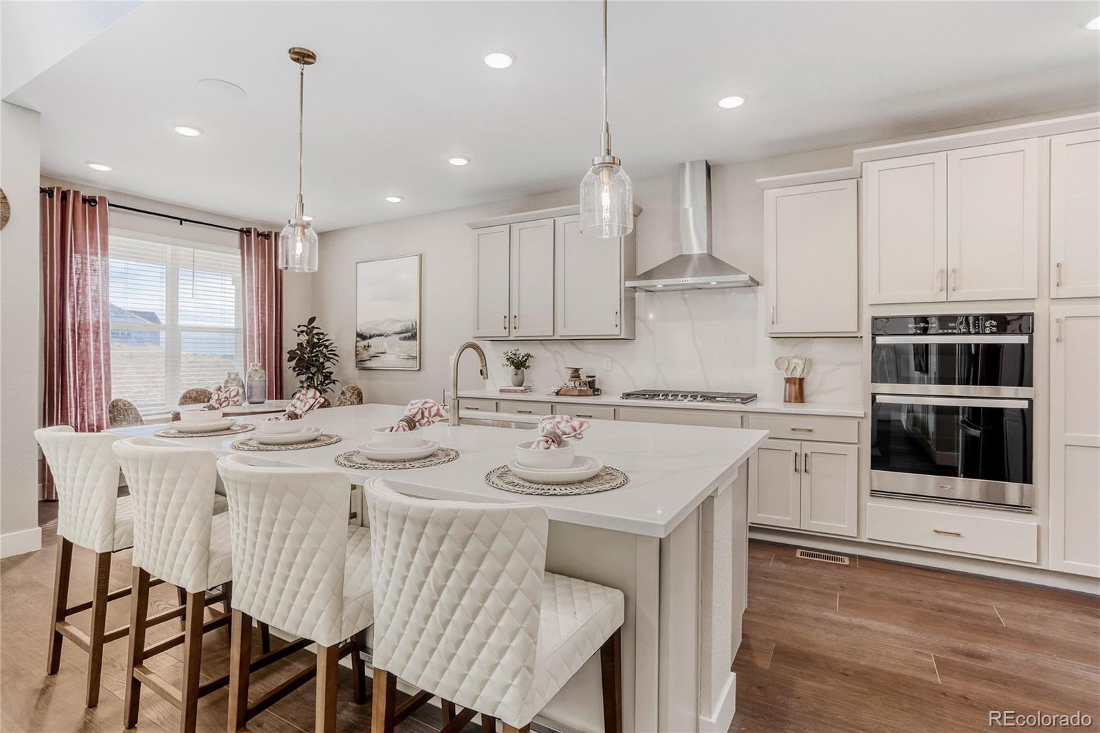 5386 Starling Way Firestone, CO 80504 - Photo 11 of 28 a kitchen with stainless steel appliances granite countertop a sink a stove a refrigerator and a dining table with wooden floor