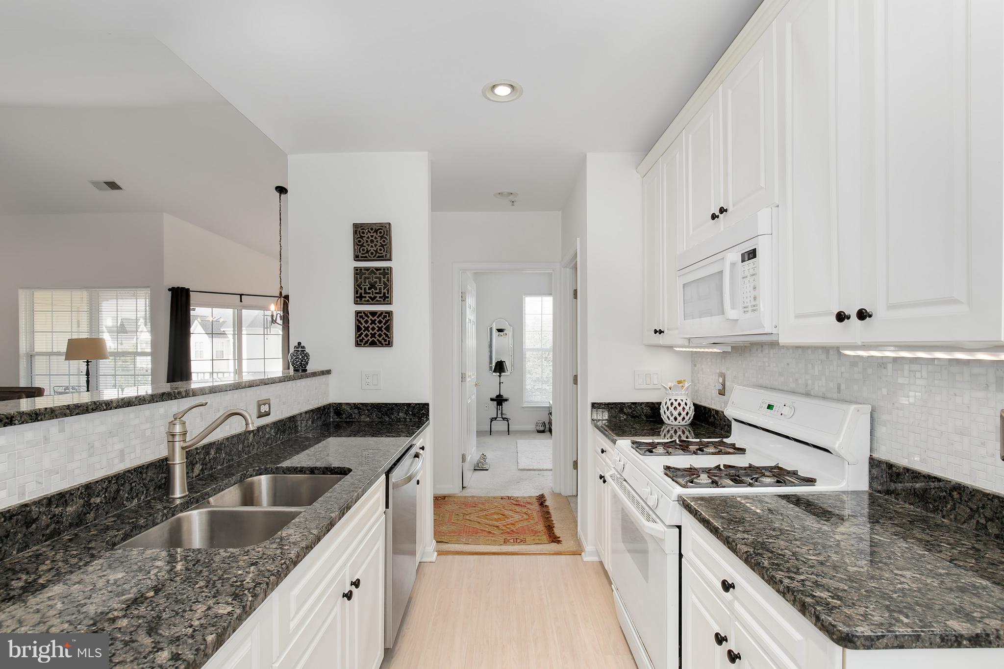 25272 Riffleford Square, Unit 304 Chantilly, VA 20152 - Photo 14 of 30 a kitchen with granite countertop a sink stove and cabinets