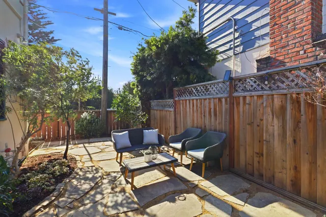a view of a patio with table and chairs potted plants and large tree