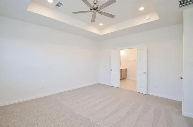 an empty room with a ceiling fan and carpet