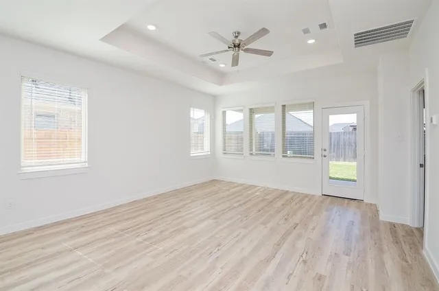 a view of an empty room with a window and wooden floor