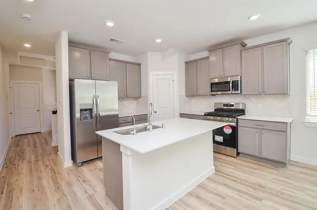 a kitchen with stainless steel appliances granite countertop a refrigerator sink and white cabinets
