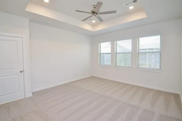 an empty room with windows and ceiling fan