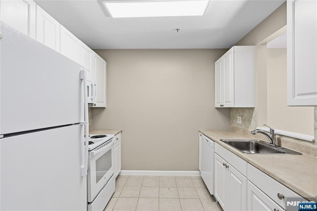 905 River Road, Unit 204 Edgewater, NJ 07020 - Photo 13 of 36 a kitchen with a sink a refrigerator and cabinets