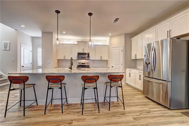 a kitchen with stainless steel appliances granite countertop a stove a sink a microwave a refrigerator and cabinets