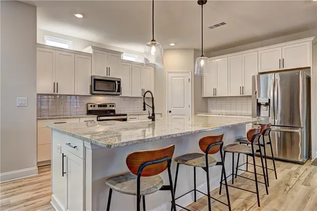 a kitchen with stainless steel appliances granite countertop a sink a oven and a wooden floors