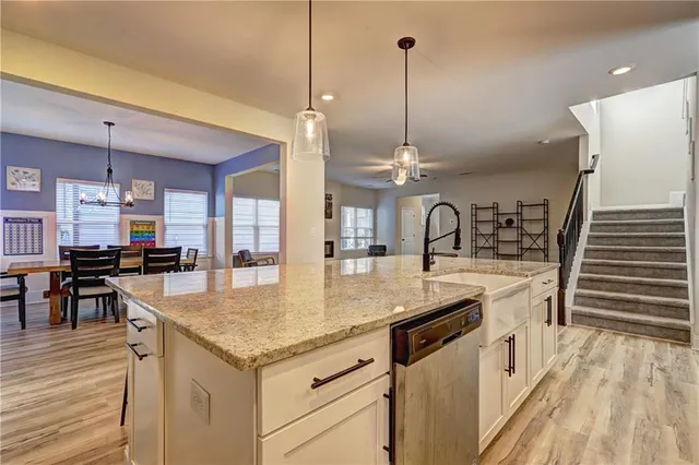 a kitchen with stainless steel appliances granite countertop a sink a stove and a wooden floors