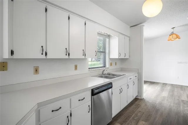 a kitchen with a sink dishwasher and cabinets with wooden floor