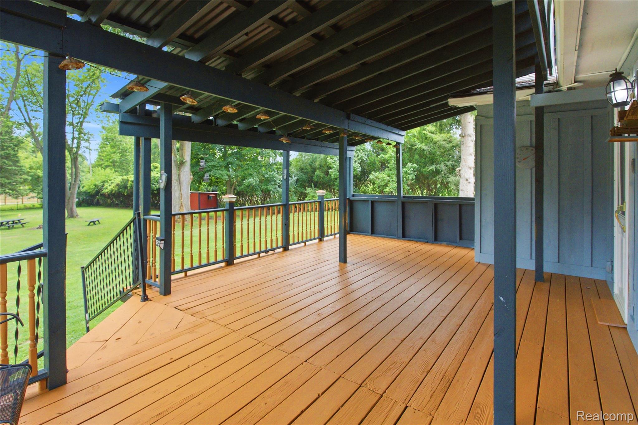4945 Miller Road Ann Arbor, MI 48103 - Photo 33 of 42 Expansive wood deck with a covered overhead structure, featuring a metal railing system, and exterior wall paneling