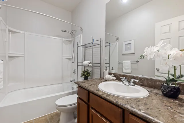 a bathroom with a granite countertop sink a toilet a mirror and shower