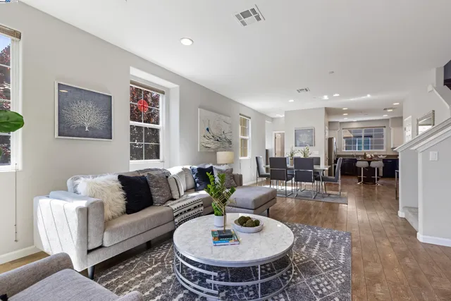 a living room with furniture and a dining table with wooden floor