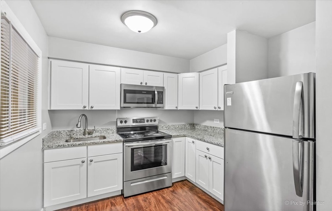 1100 North Wheeling Road, Unit 1B Mount Prospect, IL 60056 - Photo 7 of 11 a kitchen with white cabinets and white appliances